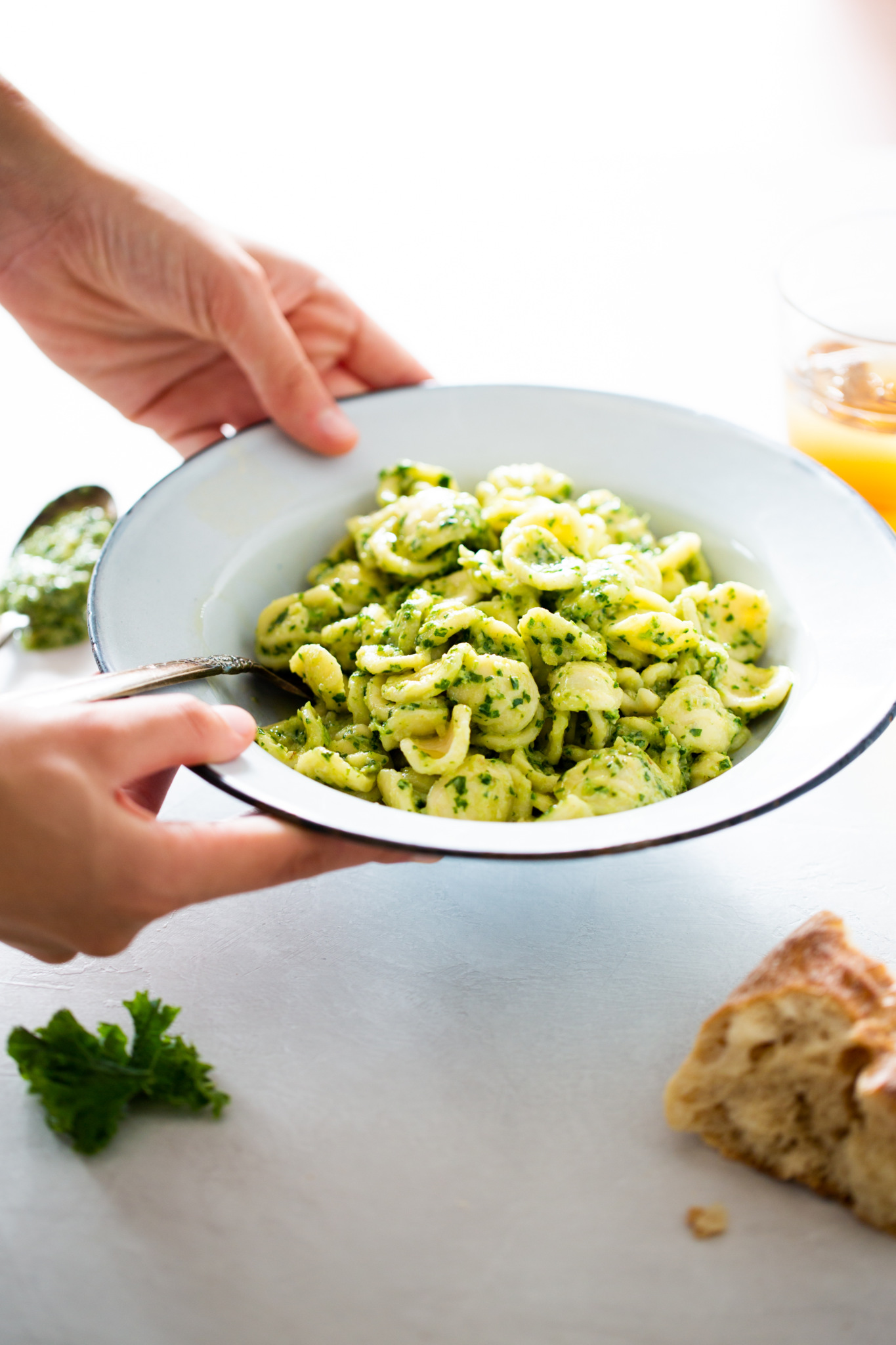 Kale pesto pasta in a dish being hold with two hands.