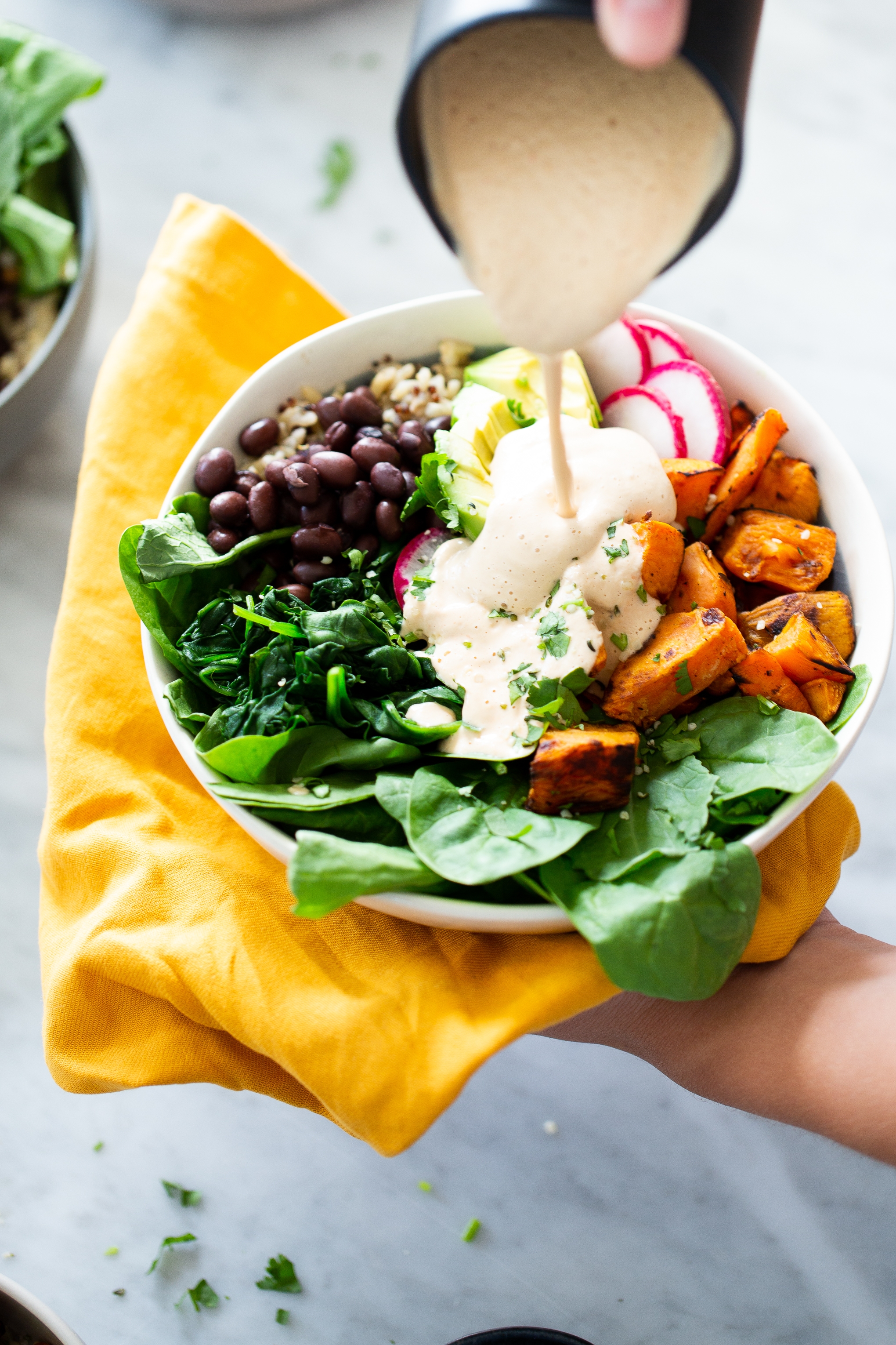 sweet potato Mexican buddha bowl with vegan creamy chipotle sauce pouring over