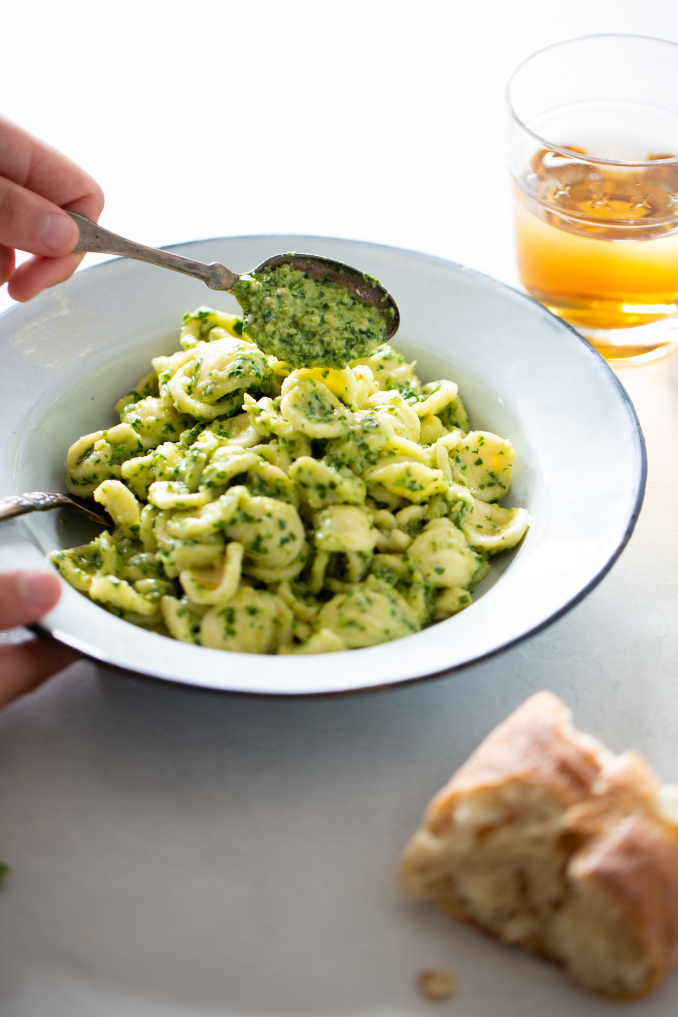 adding a spoonful of kale pesto to the pasta