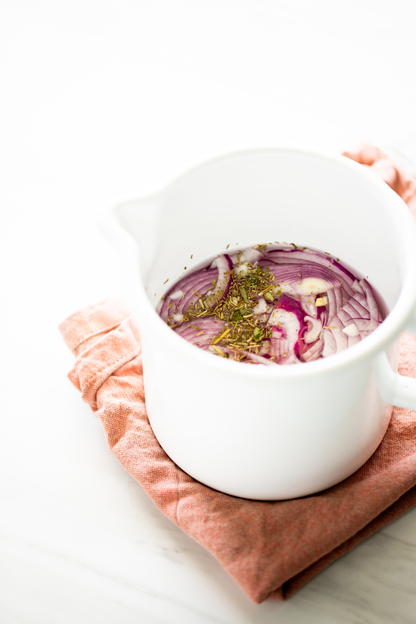 sliced red onion in a pot with dried herbs