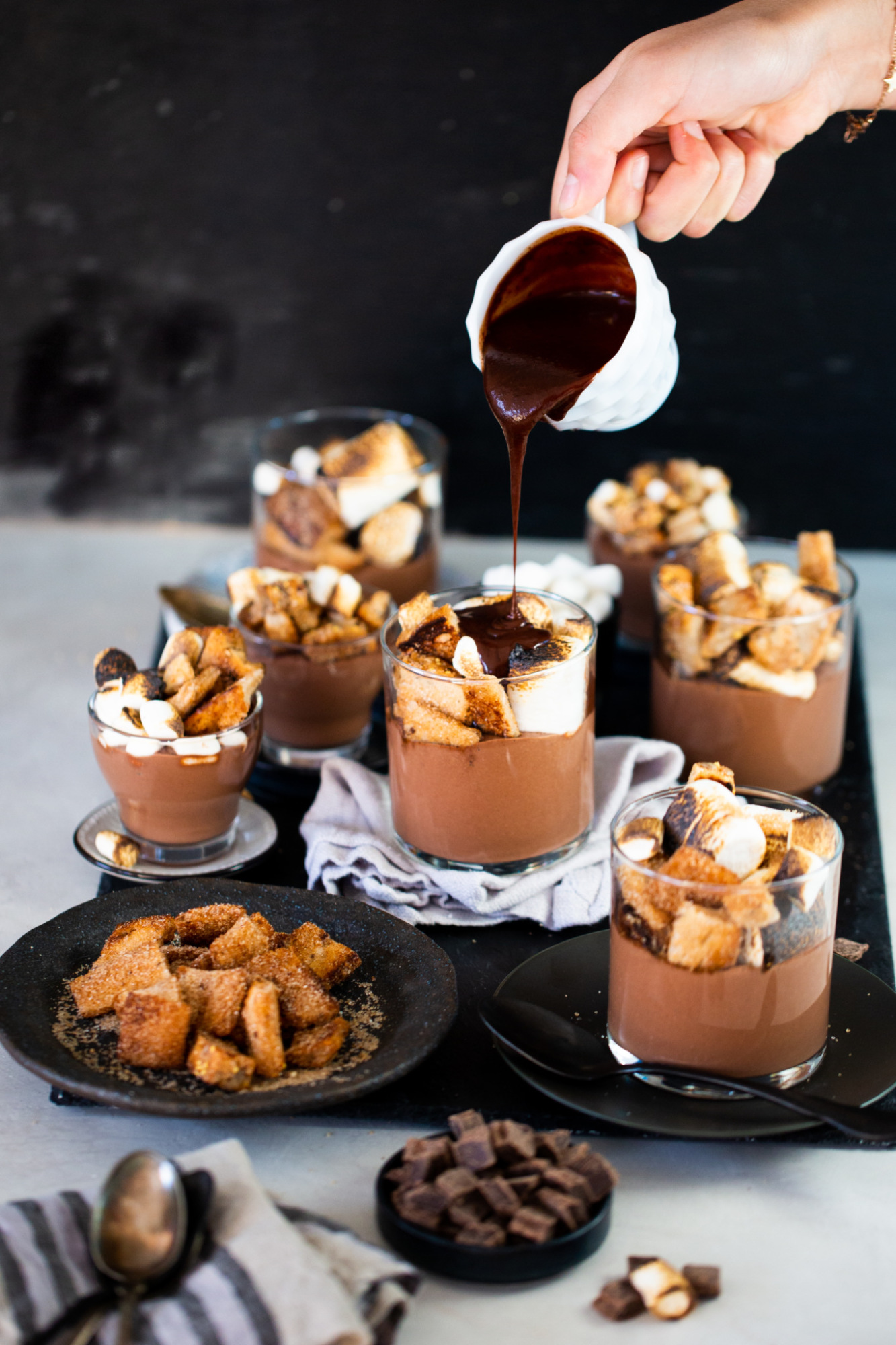 Chocolate sauce being poured over a vegan chocolate mousse.