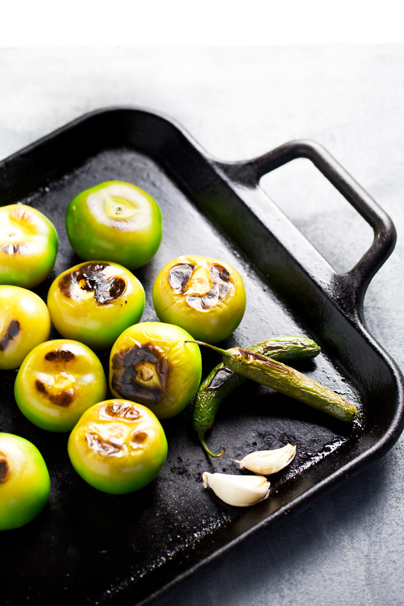 roasted tomatillos , garlic and serrano peppers on a griddle 