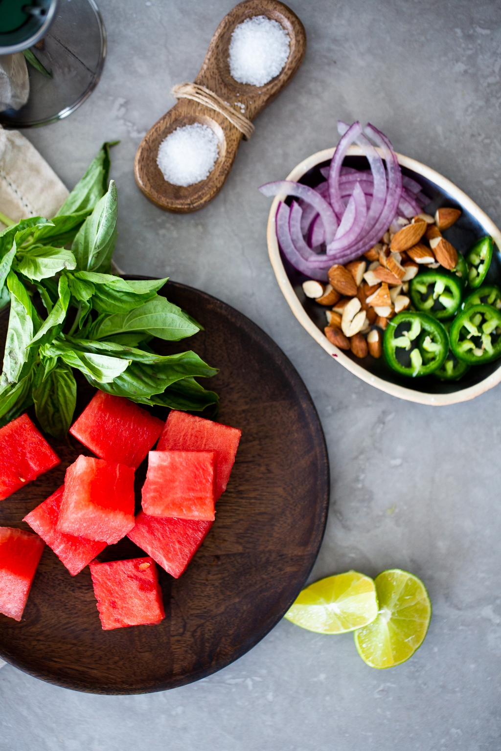 Watermelon, sliced onions, sliced chile, almonds and limes to prepare watermelon salad.