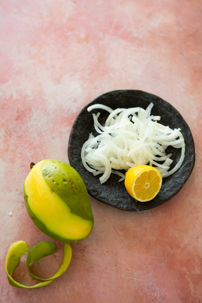 sliced onion , half a lemon and a mango half peeled