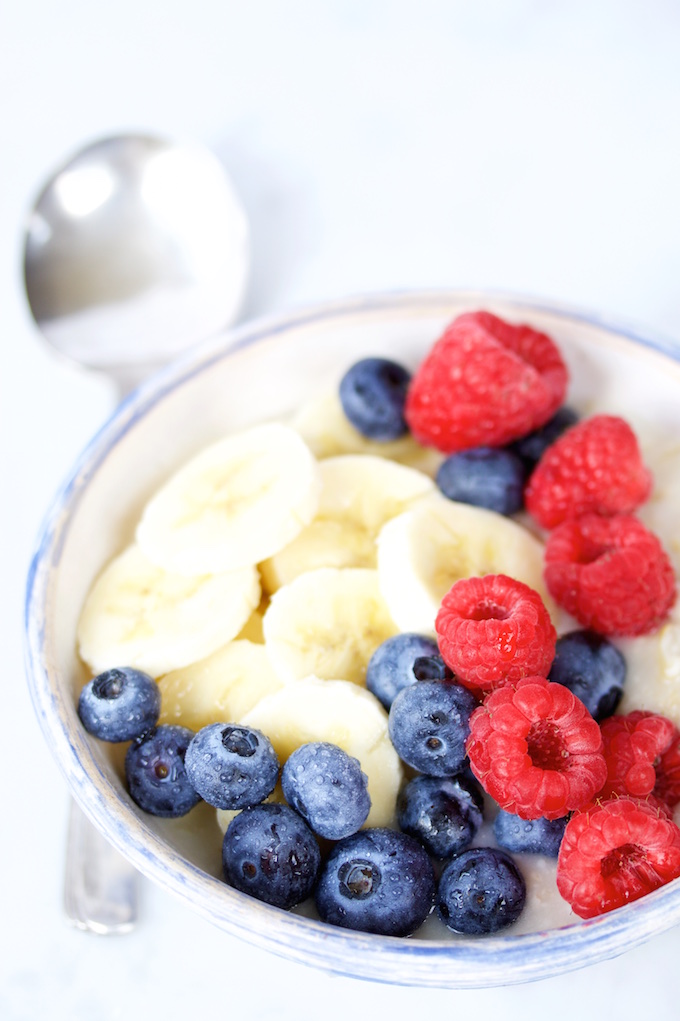 bowl of oats with sliced banans, blue berries and raspberries