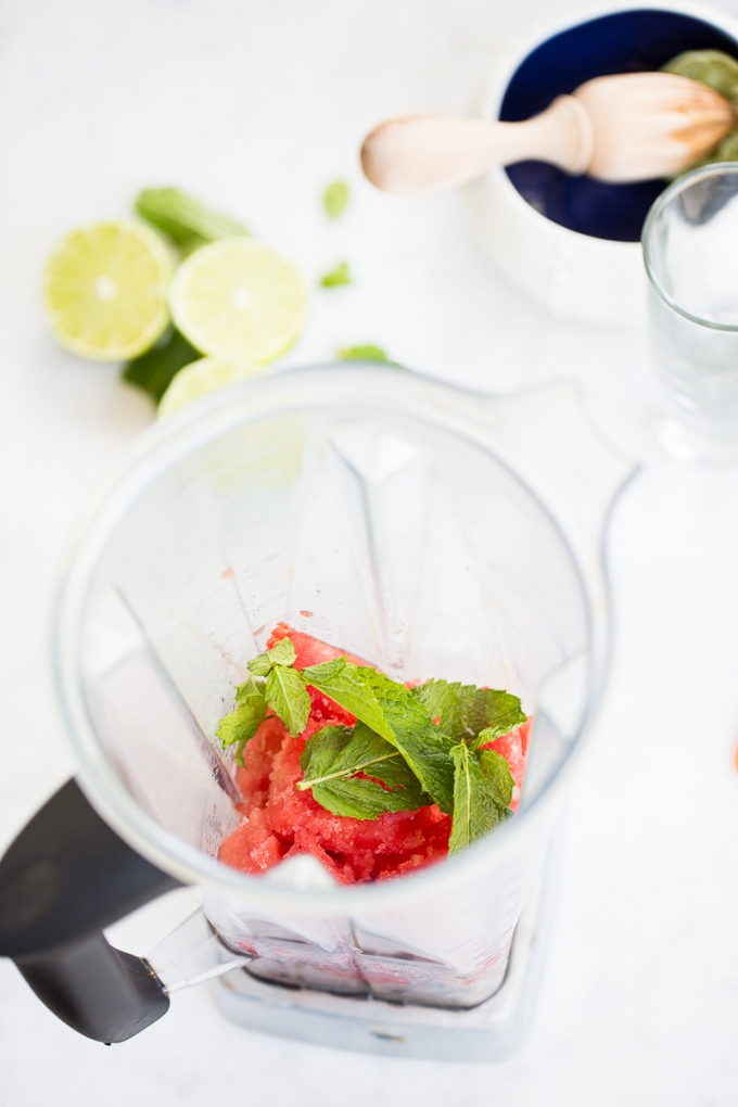 watermelon slushie in blender container with mint leaves