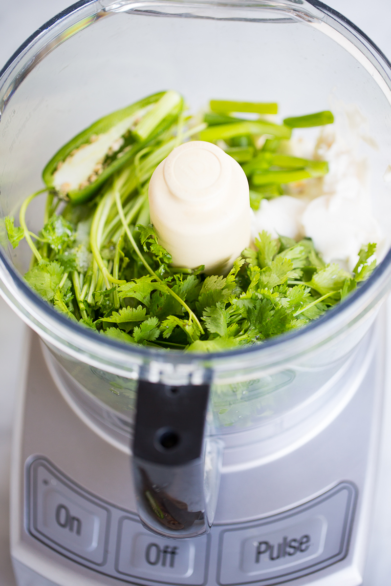 ingredients in a food processor bowl with cilantro and jalapeños for dressing