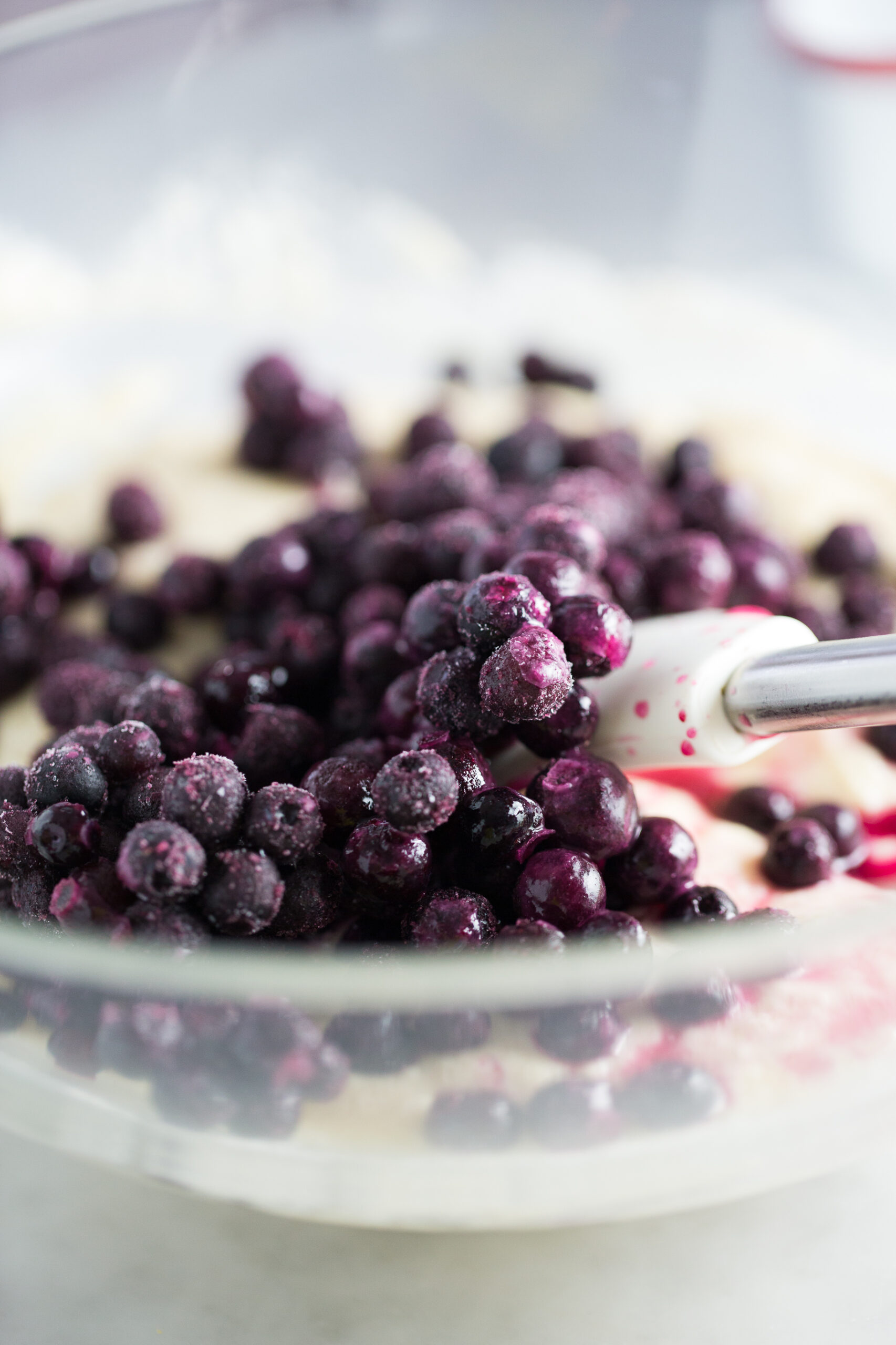 Mixing frozen blueberries into the cake batter.