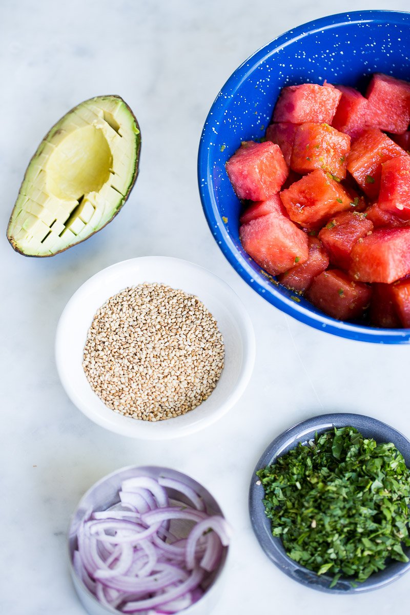 image with chopped watermelon, avocado, sesame seeds and aromatics.