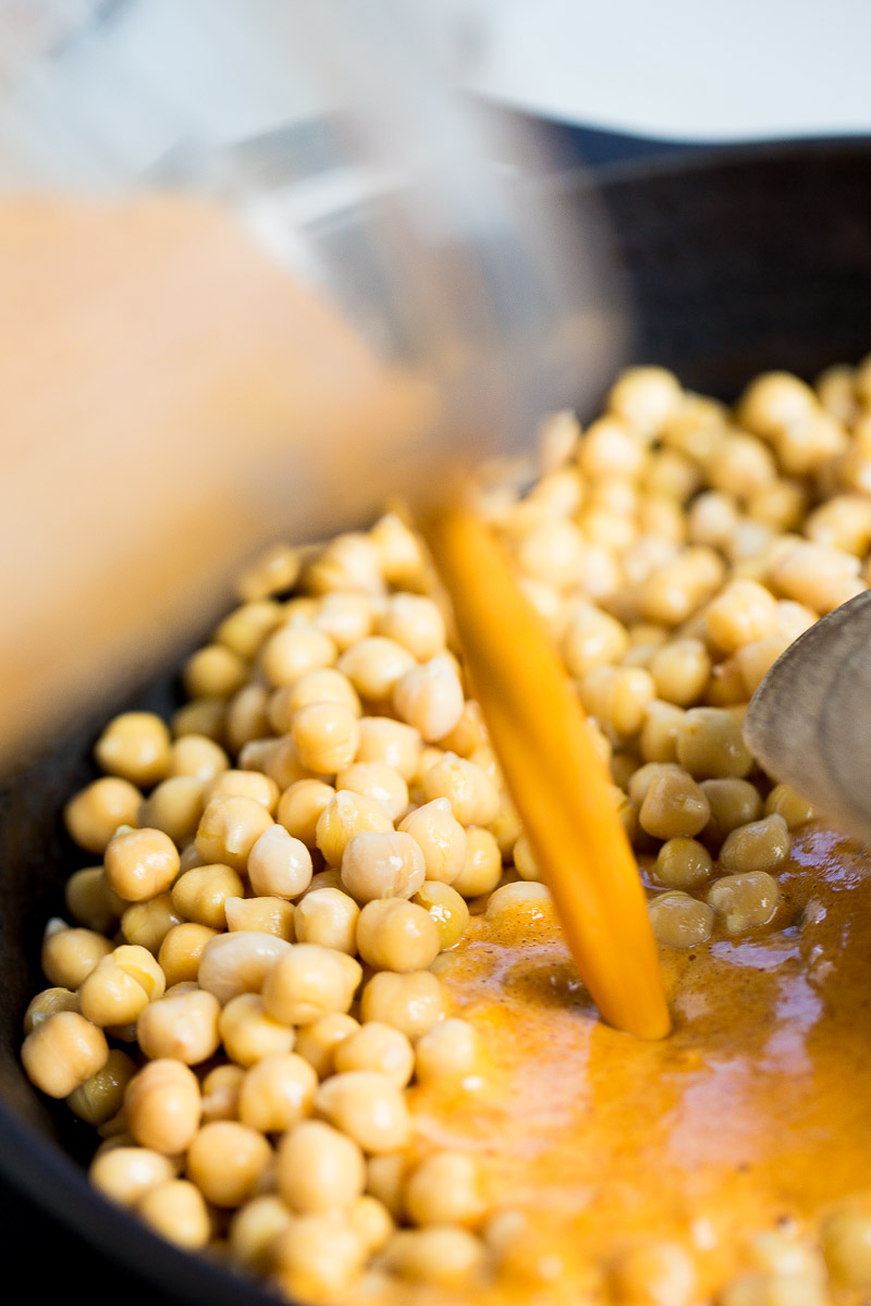 pouring Mexican mole sauce over chickpeas
