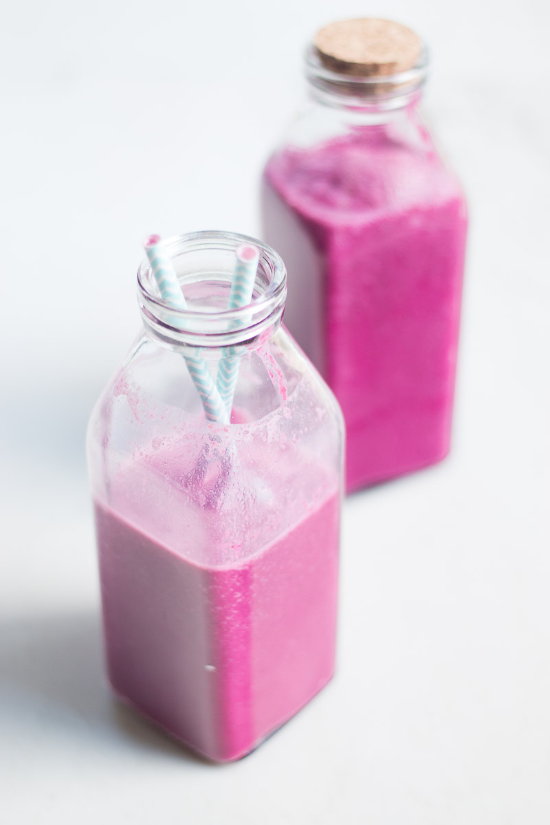 Vegan pink beet smoothie in jars with paper straws