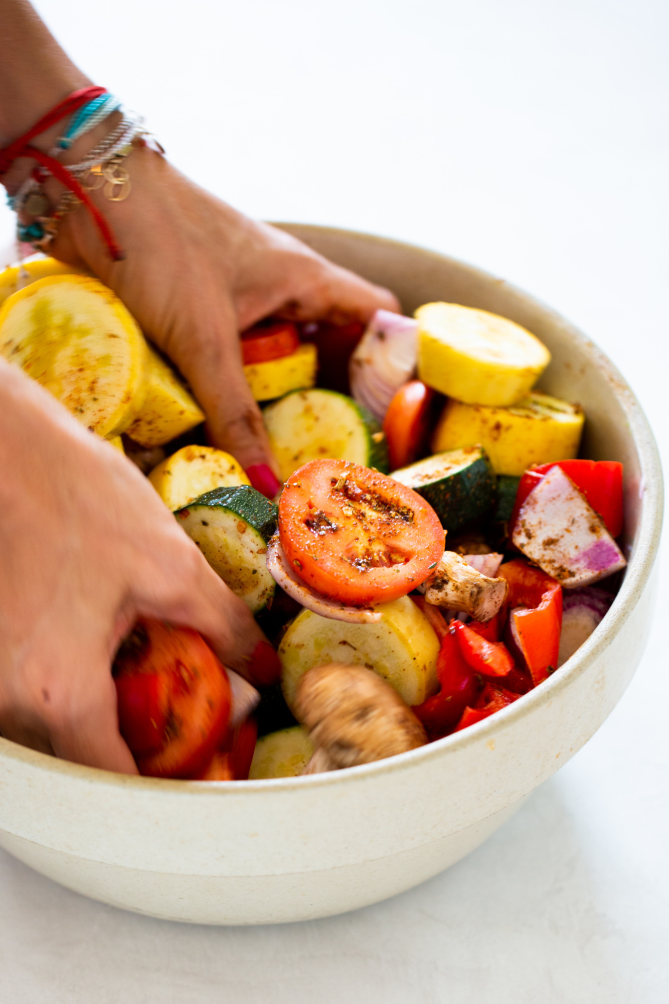 hands mixing vegetables in a bowl