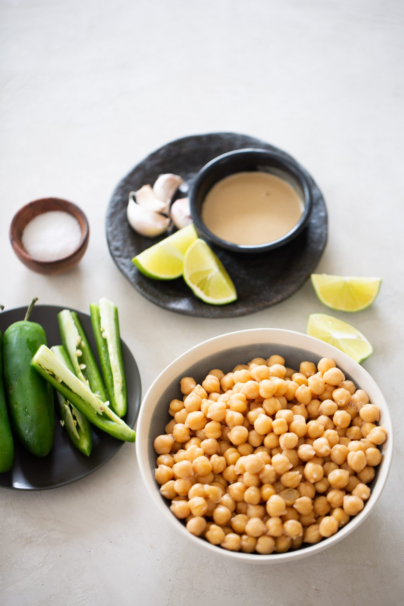 Ingredientes to make a spicy hummus with jalapenos. Chickpeas, jalapeno slices, limes, tahini and garlic.