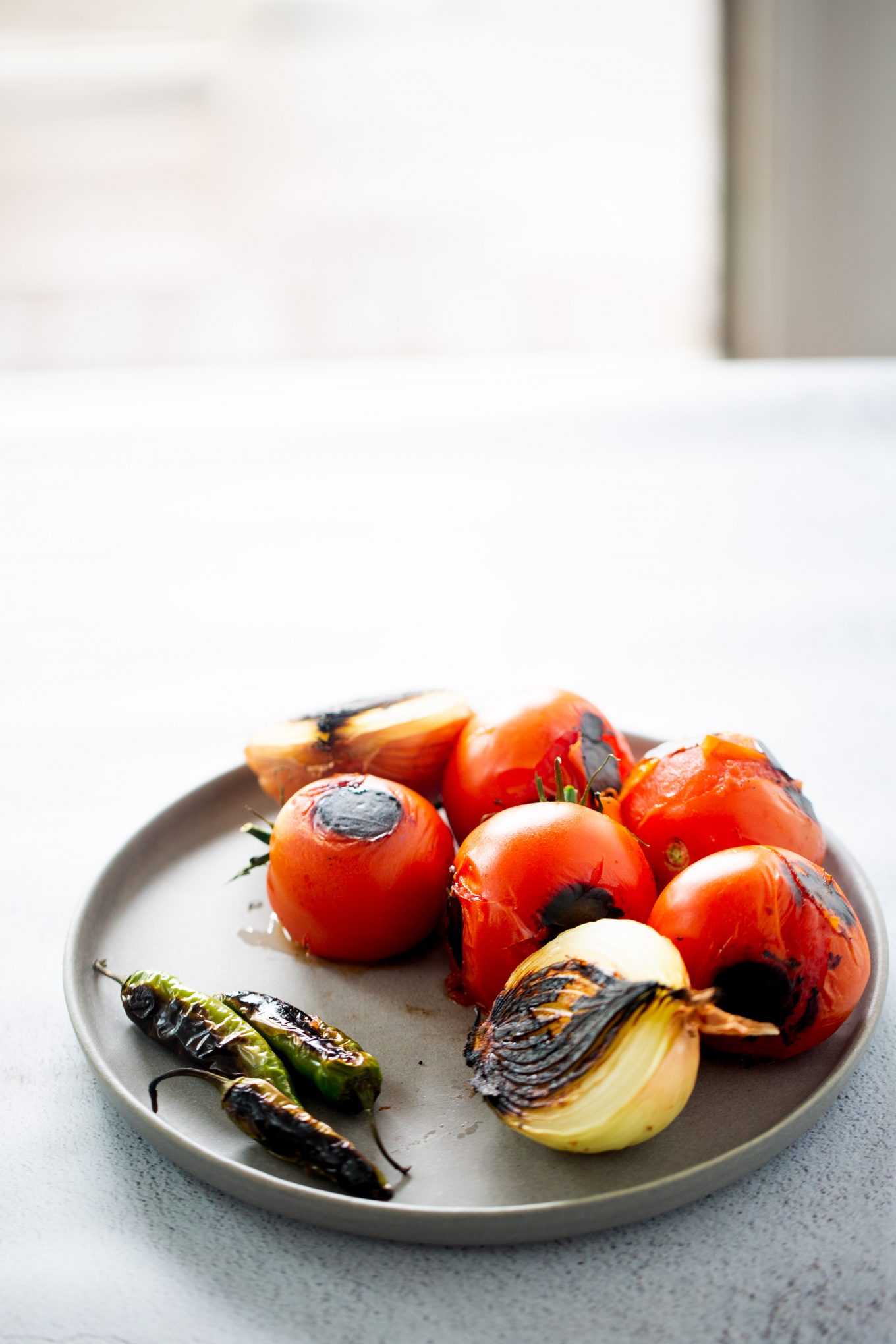 roasted tomato, onion and serranos on a gray plate ingredients