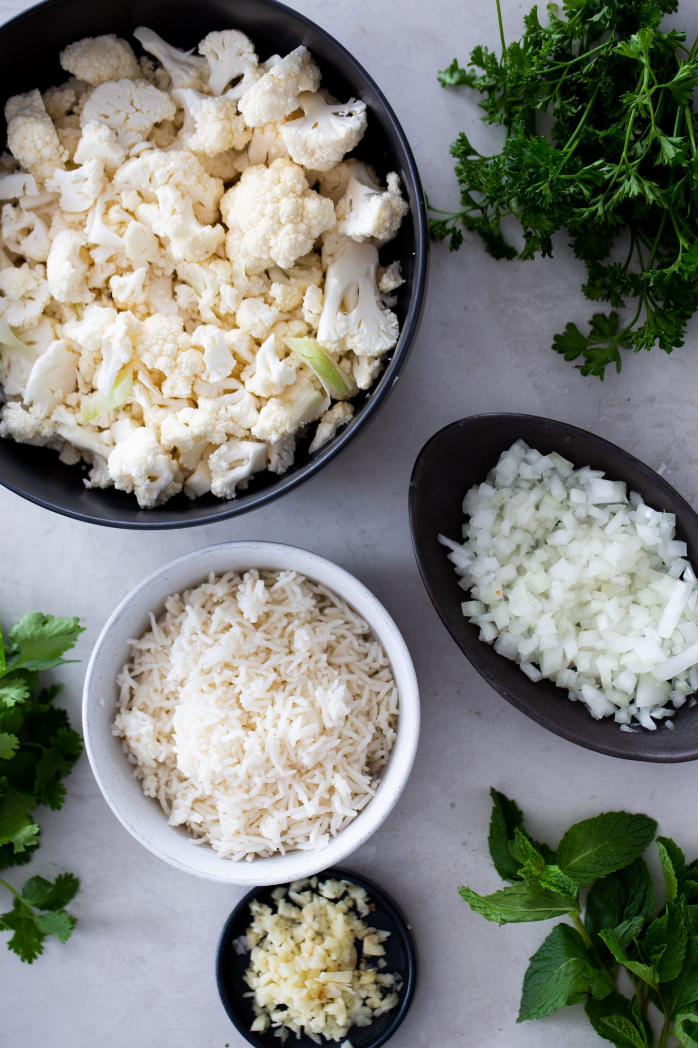 bowls with cauliflower, onion, garlic and fresh herbs