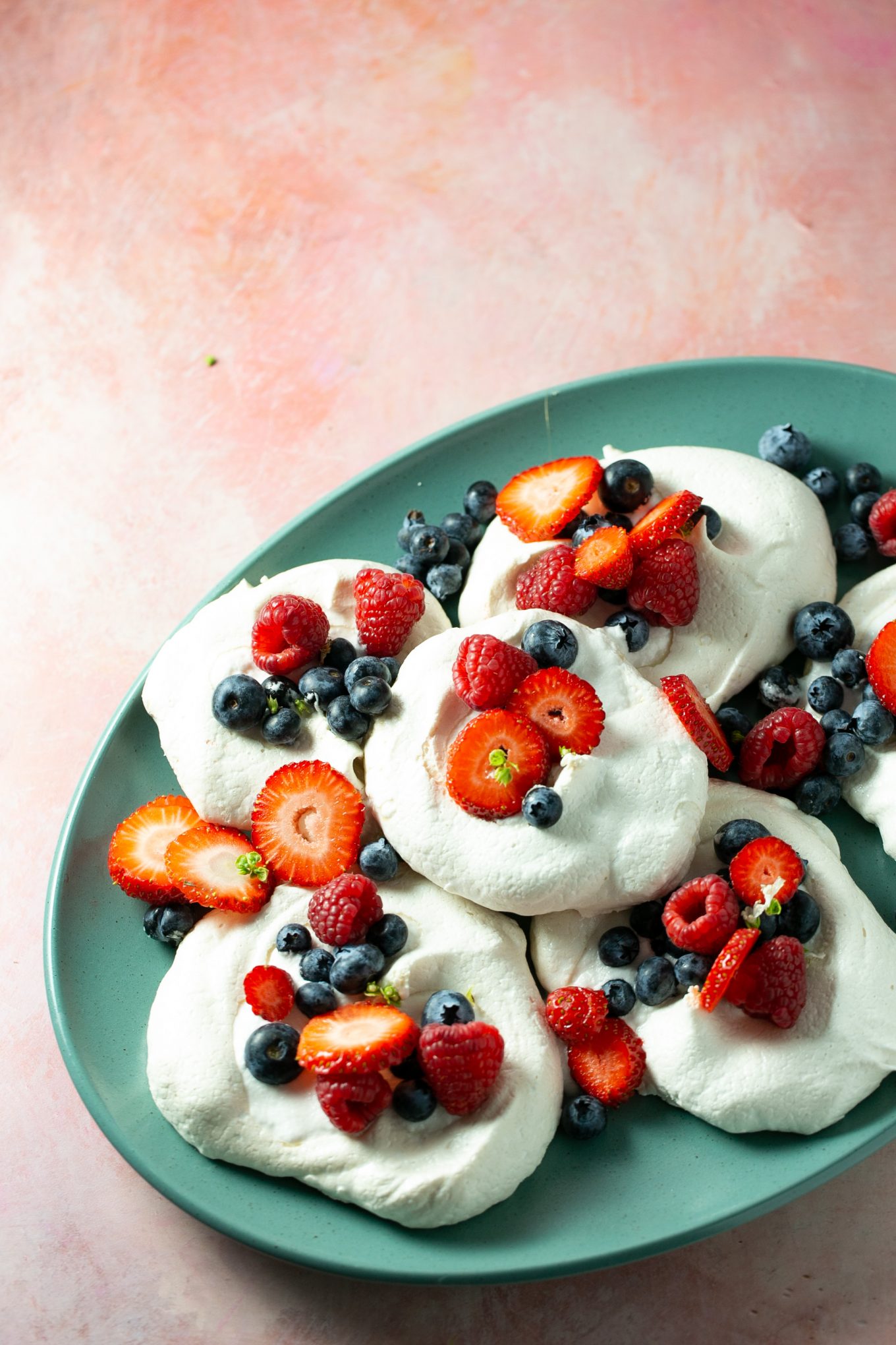 Vegan individual pavlovas topped with fresh berries and homemade coconut whipped cream