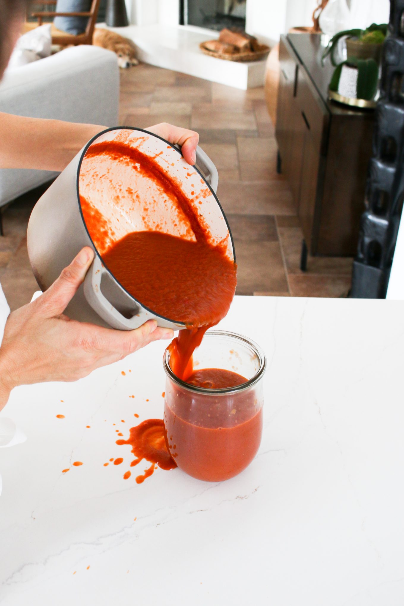 Vegan homemade red enchilada sauce being poured in a glass container.