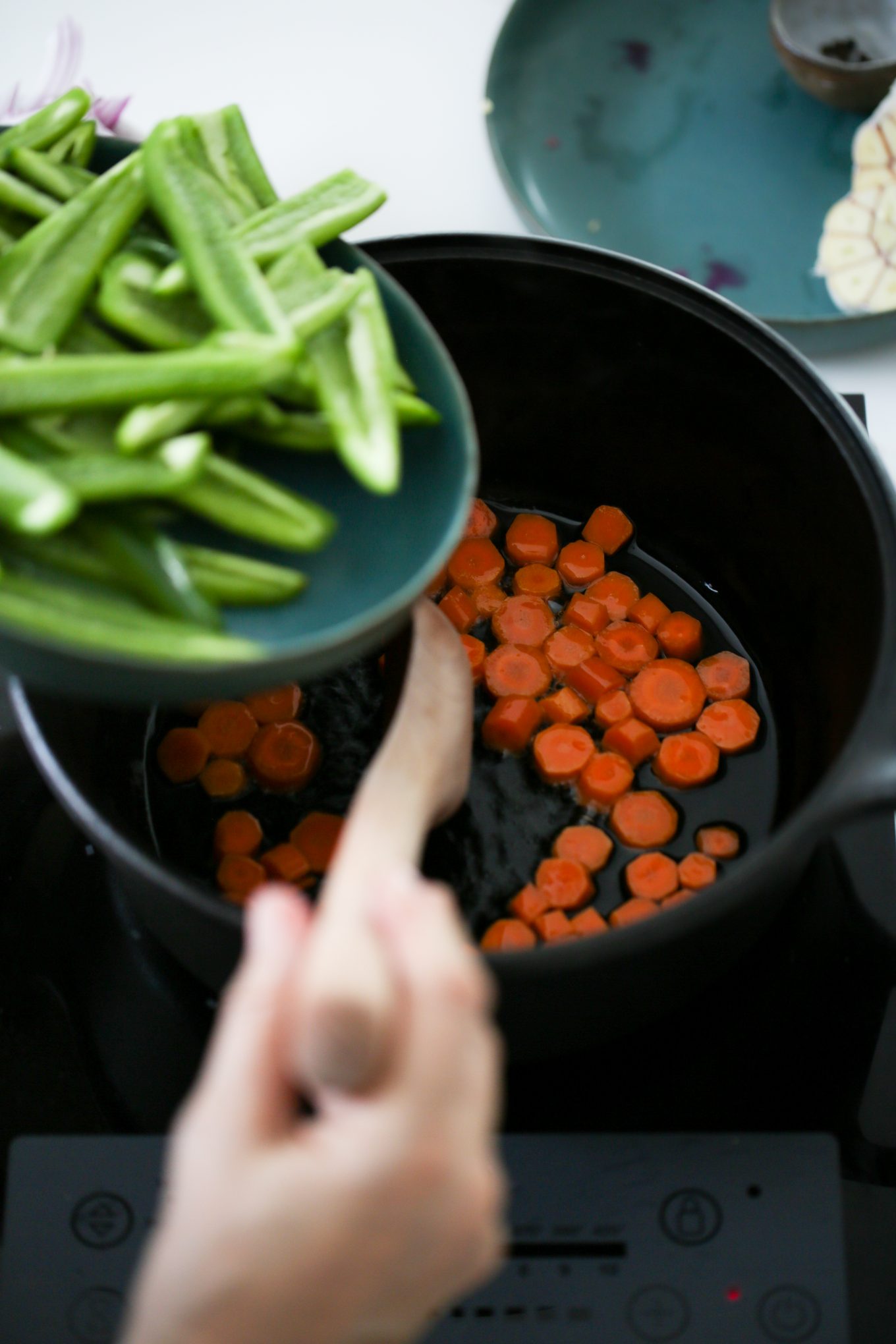 adding chiles jalapeños to a cast iron dutch ovenwith carrots in oil