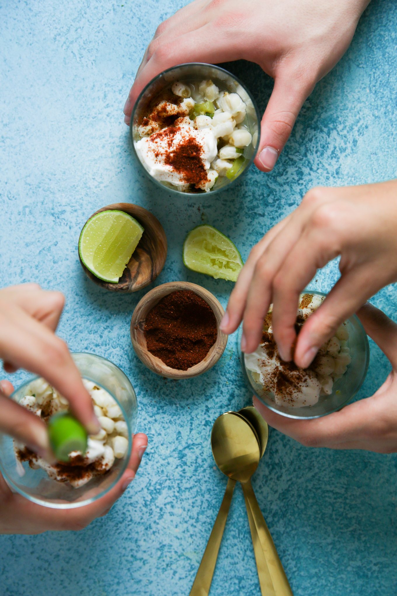 preparing the mexican esquites with chili powder, limes and salt