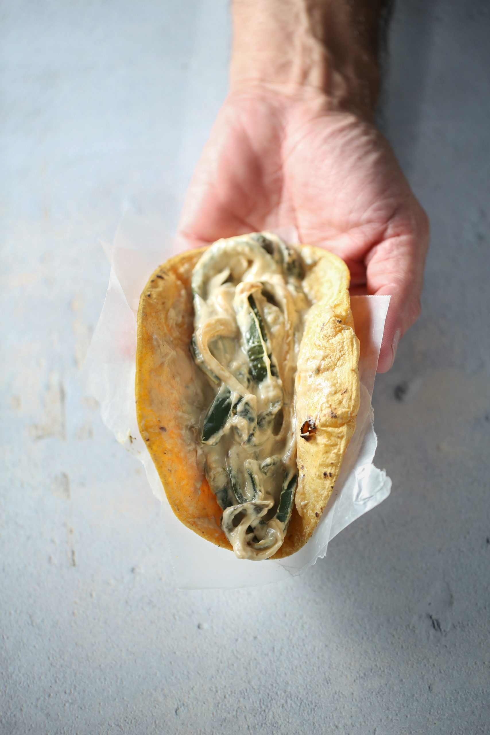 One hand one corn tortilla taco filled with vegan rajas con crema