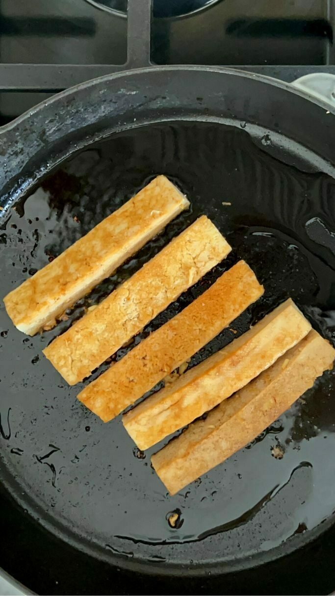 cast iron pan with oil and marinated tofu slices