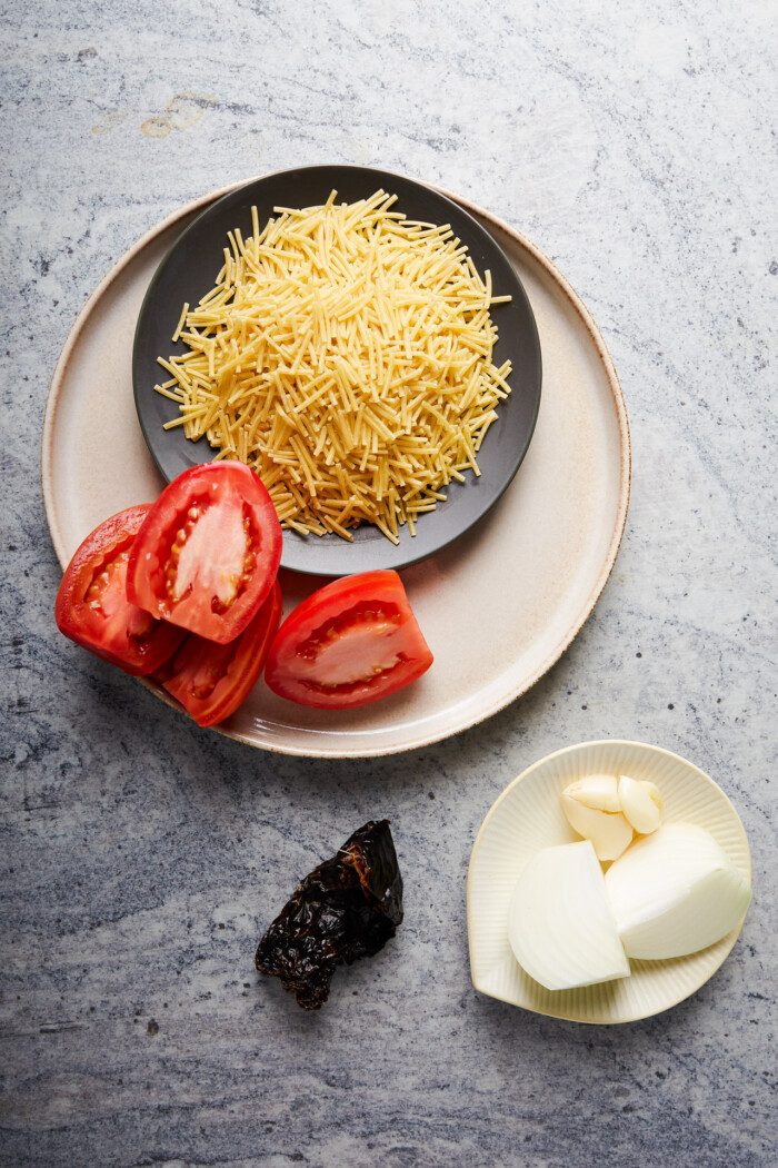 dried mexican noodles, halfed tomatoes and onion and garlic in a small dish.