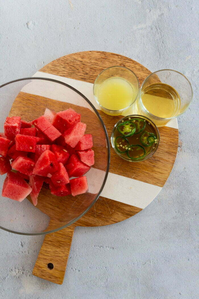 Frozen watermelon in a bowl, jalapeño syrup, lime juice and tequila to prepare spicy watermelon margaritas.