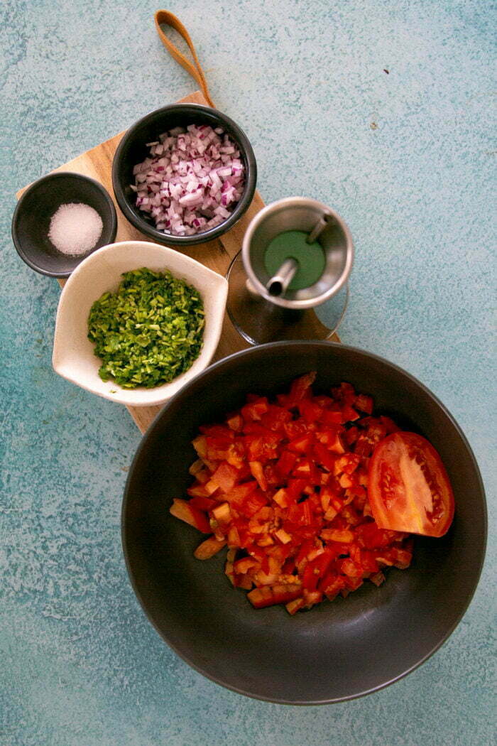 Ingredients to make pico de gallo in different bowls.