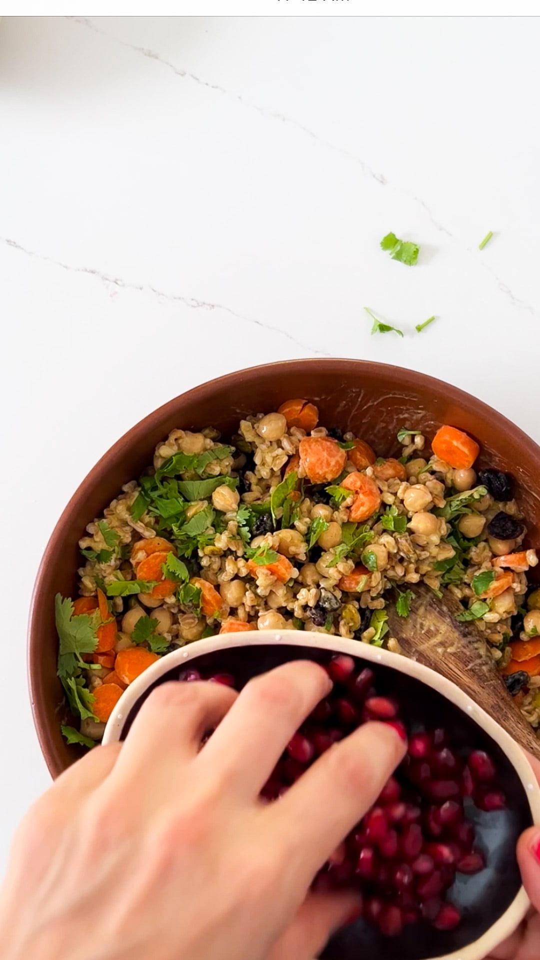 finishing the curried chickpea salad recipe with pommegranate seeds