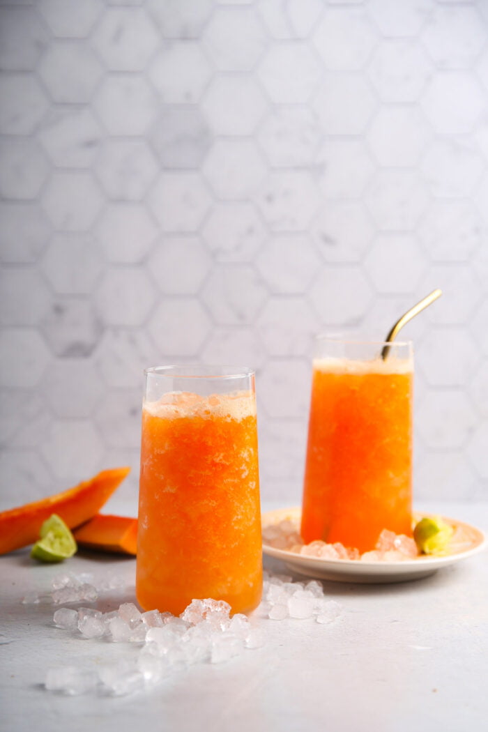 Dos vasos con agua de papaya y hielo.
