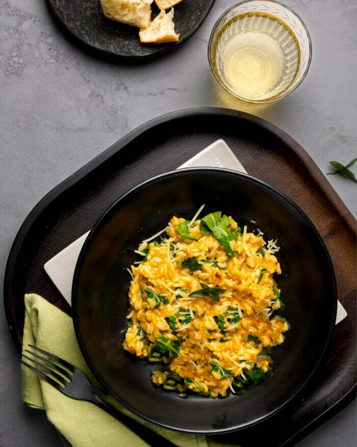 Pumpkin Oven risotto with fried sage leaves on a black pasta bwl.